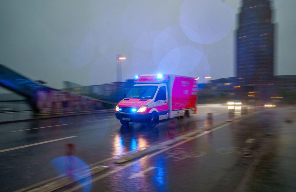 Ein Rettungswagen fährt bei Regen über eine Brücke