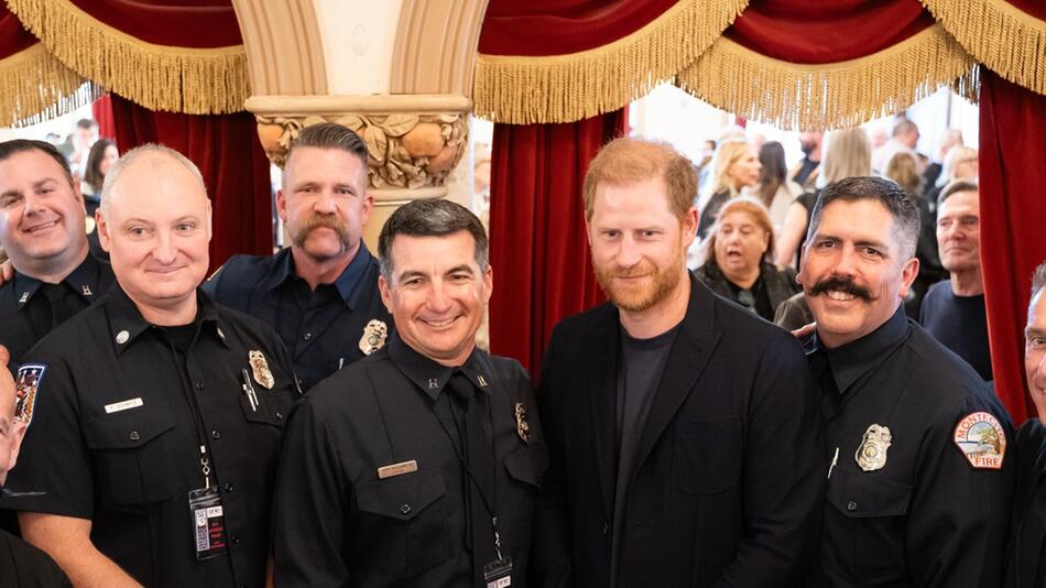 Prinz Harry posiert mit Ersthelfern der Feuerkatastrophe.