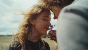 Junges Paar, er hält er ihr eine Blume unter die Nase, sie schnuppert daran. 