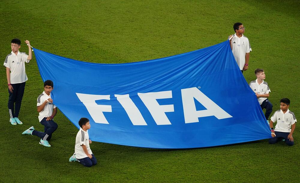 Kinder und Jugendliche präsentieren die Fahne des Fussballweltverbands Fifa