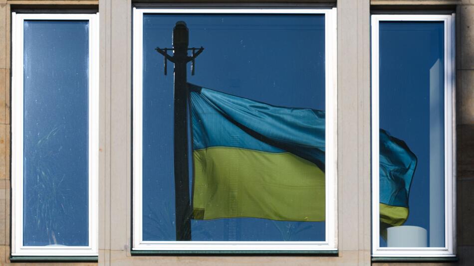 Eine Fahne der Ukraine spiegelt sich in einem Fenster