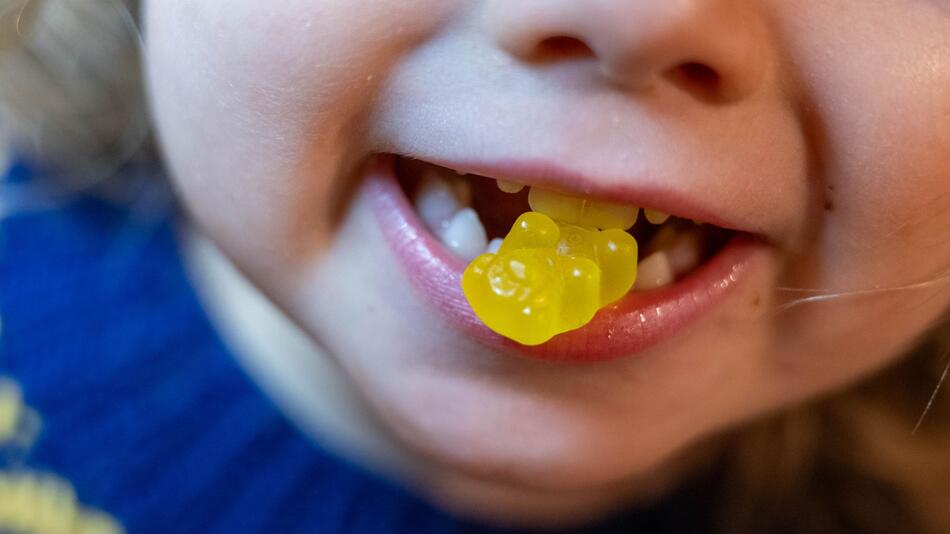 Ein Kind beisst auf ein Gummibärchen