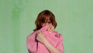 Eine Frau verdeckt ihr Gesicht mit einem pinkfarbenen Shirt
