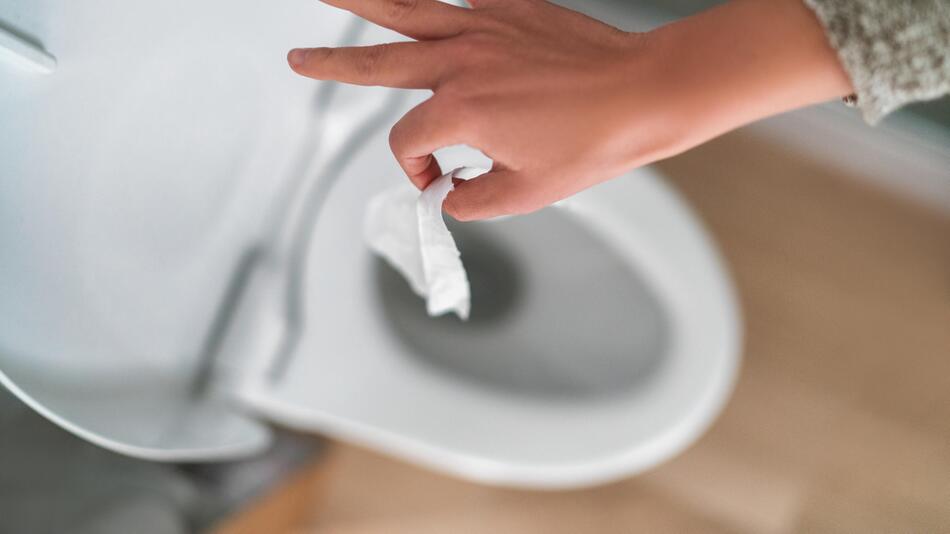 Frau wirft Feuchttuch in Toilette