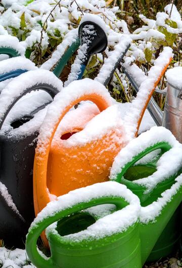 Giesskannen mit Schnee überdeckt