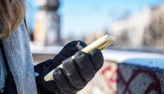 Eine warm angezogene Frau hält bei Kälte ein Handy