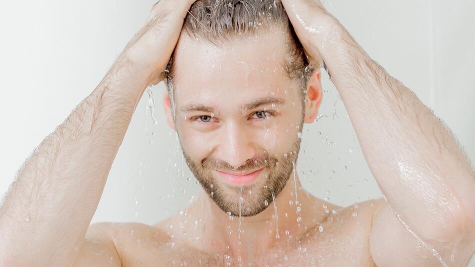 Mann steht unter einer Dusche