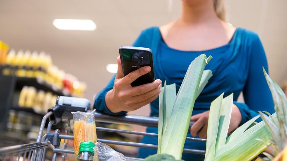 Eine Frau mit Smartphone im Supermarkt