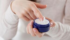 Eine Frau streicht mit dem Finger durch eine Cremedose