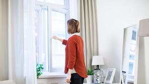 Eine junge Frau öffnet in einer Wohnung das Fenster