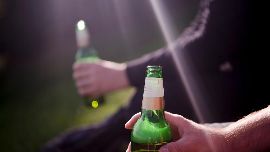 Zwei Männer sitzen im Olympia-Park und trinken Bier