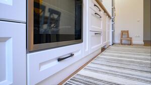 Eine weisse Schublade unter einem Ofen.