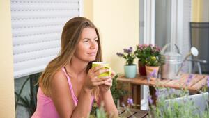 Frau sitzt auf einem Balkon und trinkt Kaffee