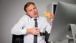 Mann im Büro mit Kaffee und Burger.

