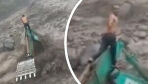 Inmitten der Fluten: Arbeiter rettet sich vor reissendem Wasser auf Bagger