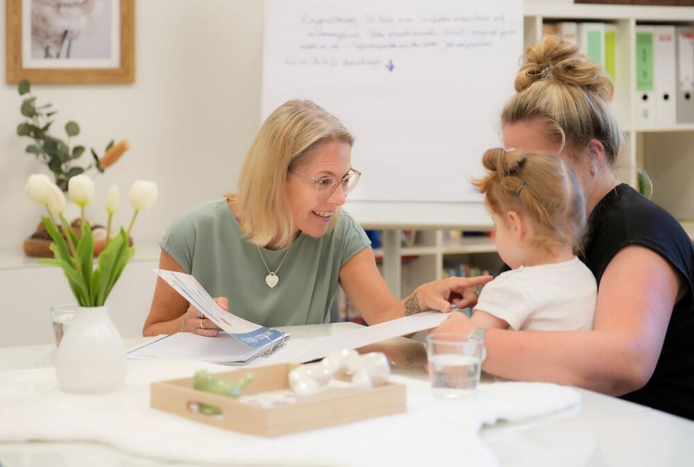 Tanja Vossen im Gespräch mit einer Mutter und ihrem Kind