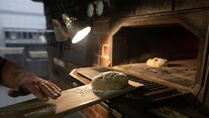 Teig wird auf einem Brotschieber in einen Ofen geschoben