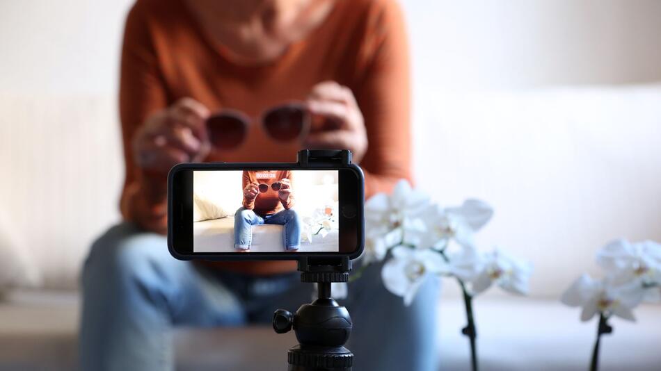 Influencerin folmt sich mit Sonnenbrille in den Händen
