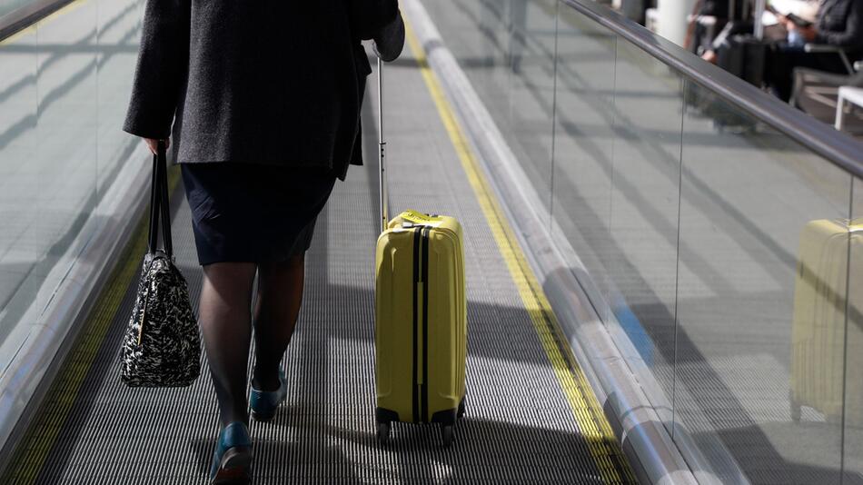 Eine Frau mit Rollkoffer am Flughafen