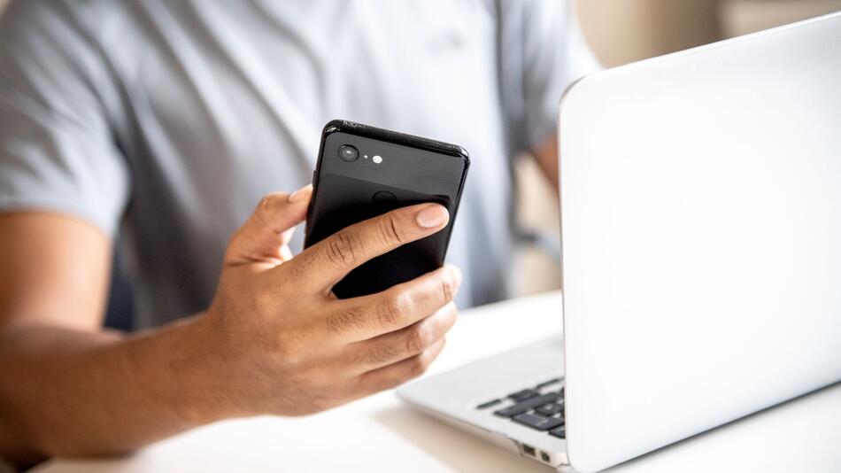 Mann mit Smartphone und Laptop