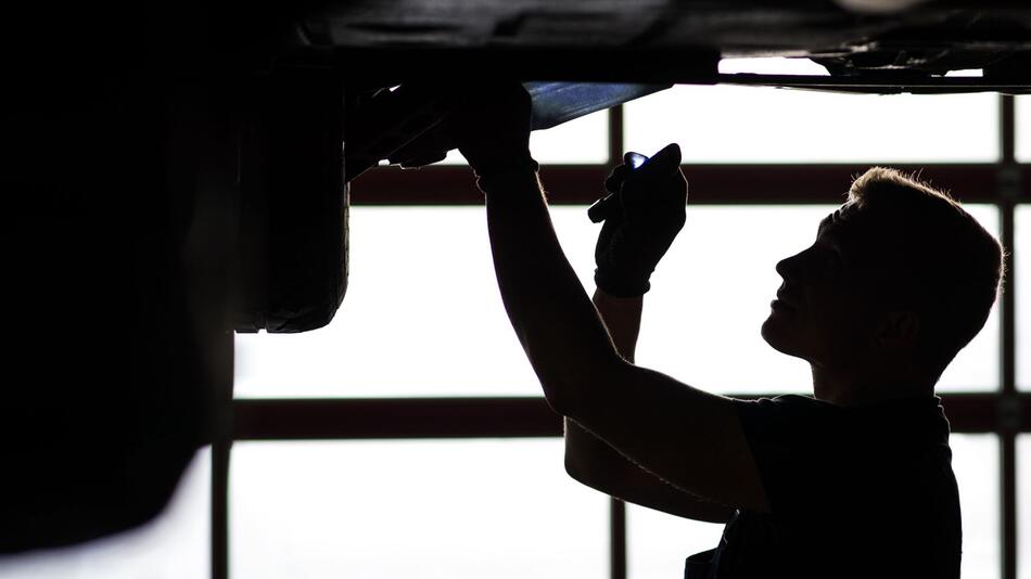 Ein Mechaniker begutachtet ein KFZ in einer Autowerkstatt
