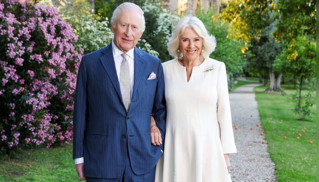 König Charles und Königin Camilla grüssen von der Weihnachtskarte in frühlingshafter Umgebung.