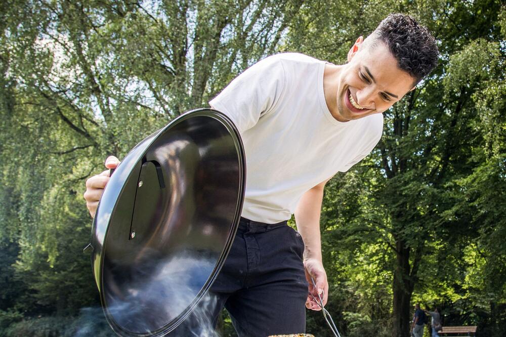 Ein Mann öffnet einen Grill