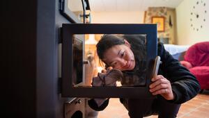 Eien Frau putzt gebückt eine Kaminscheibe.