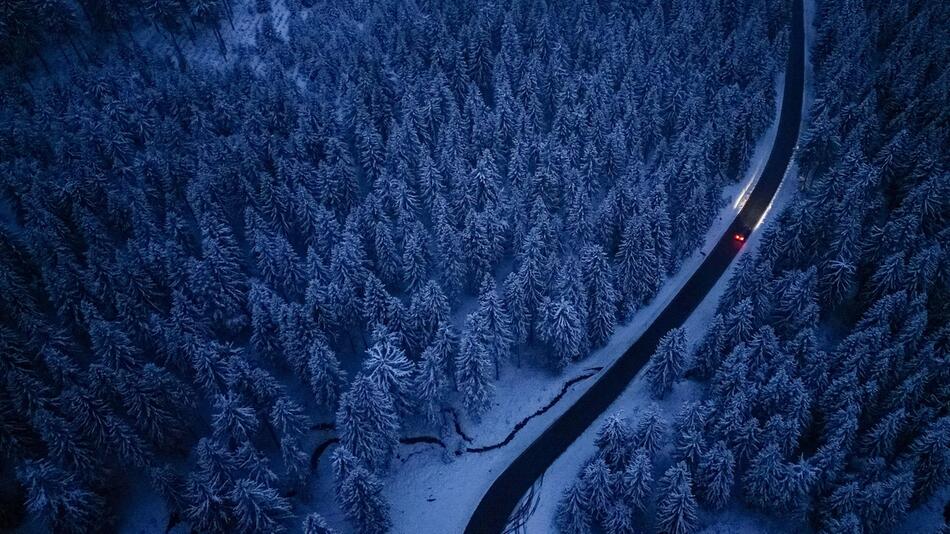 Ein Auto fährt durch den Winterwald im Erzgebirge