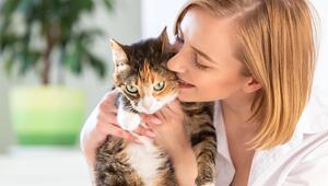 Lächelnde Frau in weissem Hemd küsst eine Katze.