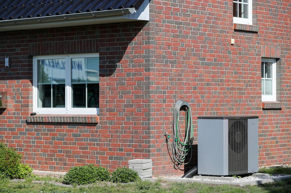 Eine Luft-Wasser-Wärmepumpe steht vor einem Haus
