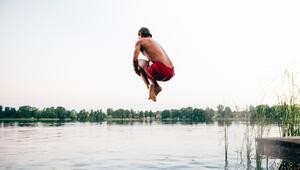 Junger Mann springt vom Steg in den See