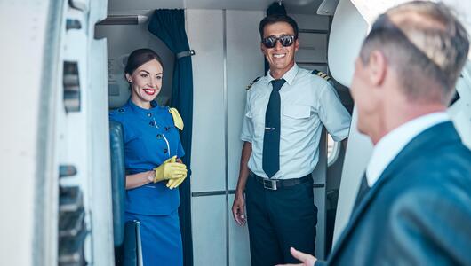 Flugbegleiterin und Pilot begrüssen Fluggast