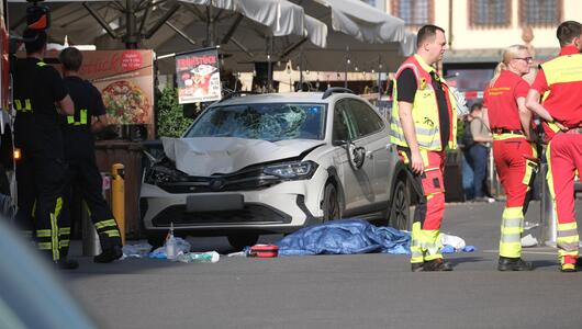 Rettungskräfte stehen neben einem beschädigten Auto in Leipzig