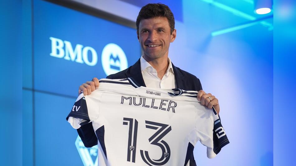 Stolz zeigt Thomas Müller bei einer Pressekonferenz in Vancouver sein Trikot, das ebenfalls ...