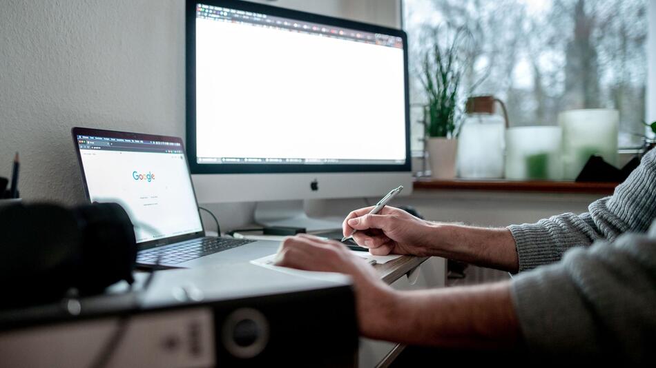 Eine Person sitzt an einem Schreibtisch vor einem Computer