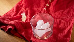 Glas mit Eiswürfeln steht auf einem Shirt mit Kaugummi-Fleck