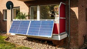 Balkon mit zwei grossen blauen Solarpaneelen an der Brüstung, rotem Sichtschutz, mehreren ...