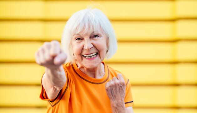 Seniorin, die gut gelaunt und sportlich aktiv ihre Faust nach vorne streckt