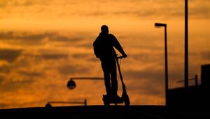 Mann fährt mit einem E-Scooter über eine Brücke