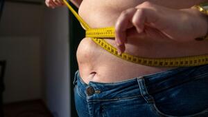 Eine Frau mit Übergewicht hält ein Massband um ihren Bauch.