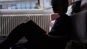 Ein Kind liest an eine Couch gelehnt