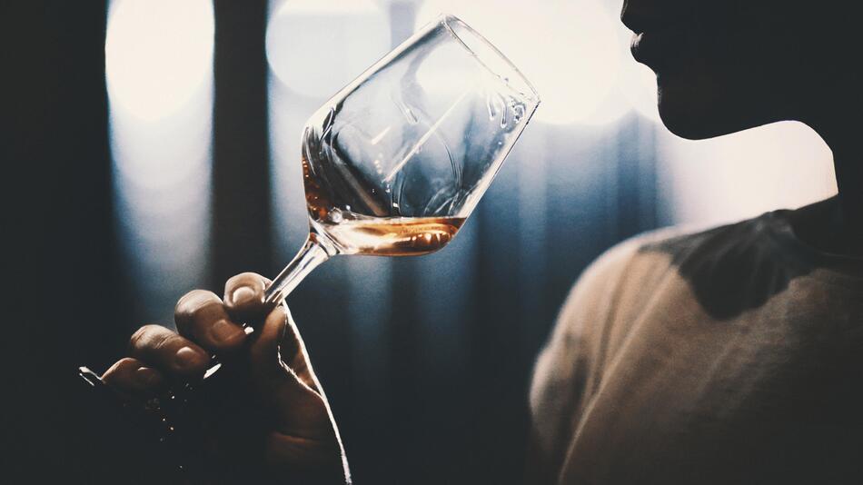 Person, die ein Glas Wein zum Mund führt