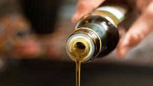 Nahaufnahme einer Hand, die Öl aus einer Flasche giesst