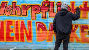 Ein Schüler sprüht Graffiti mit "Wehrpflicht Nein Danke"