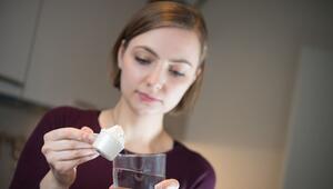 Frau gibt Proteinpulver in ein Wasserglas