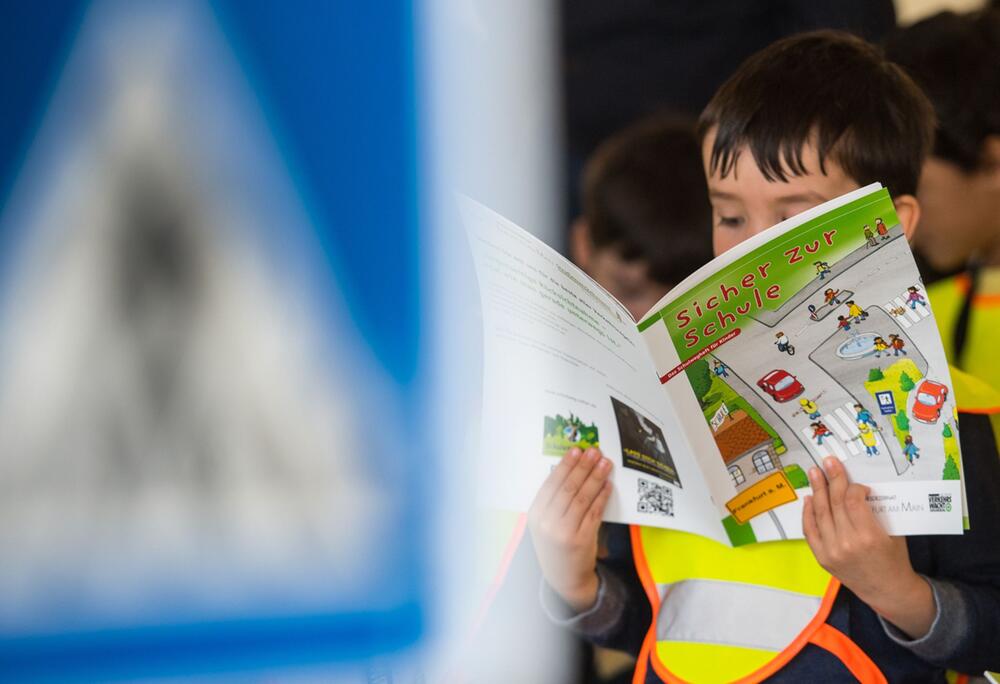Ein Junge hält die Broschüre "Sicher zur Schule"