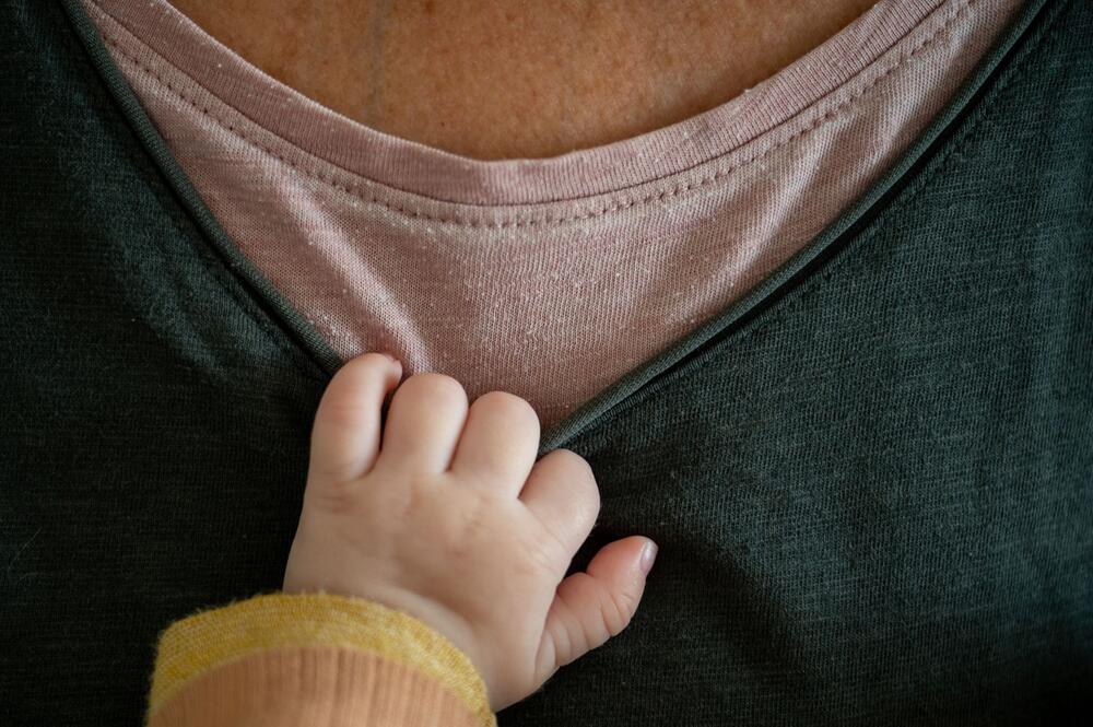 Ein Baby hält sich am T-Shirt der Mutter fest