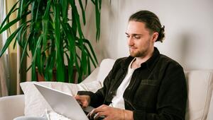 Ein junger Mann nutzt einen Laptop auf dem Sofa