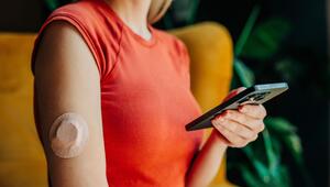 Eine Frau misst ihre Blutzuckerwerte mit Sensor und Smartphone